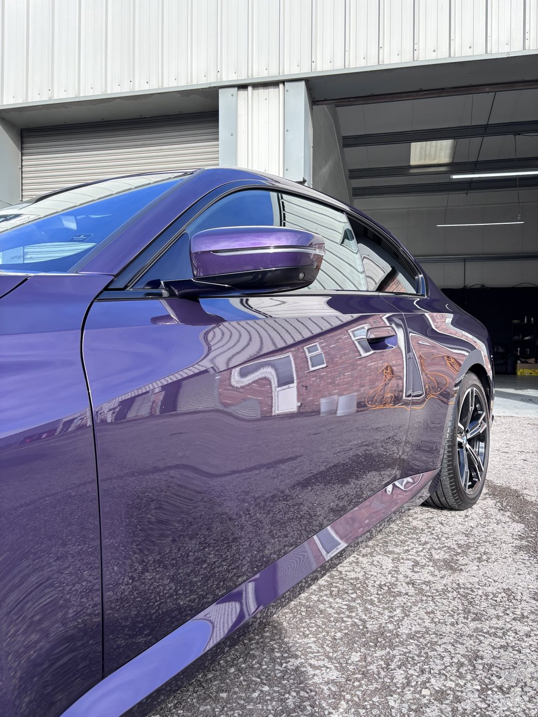 Reflections of the Bridgend unit in the coated door of a purple BMW 220i