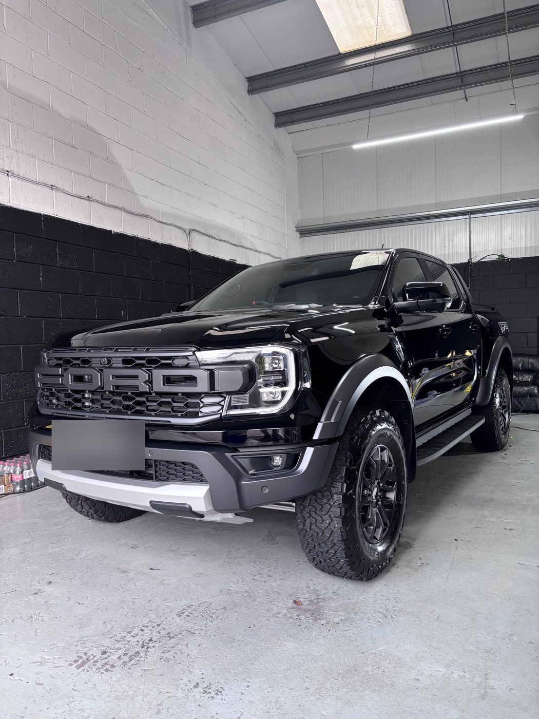Front three-quarter of a ceramic coated black Ford Ranger Raptor in the unit