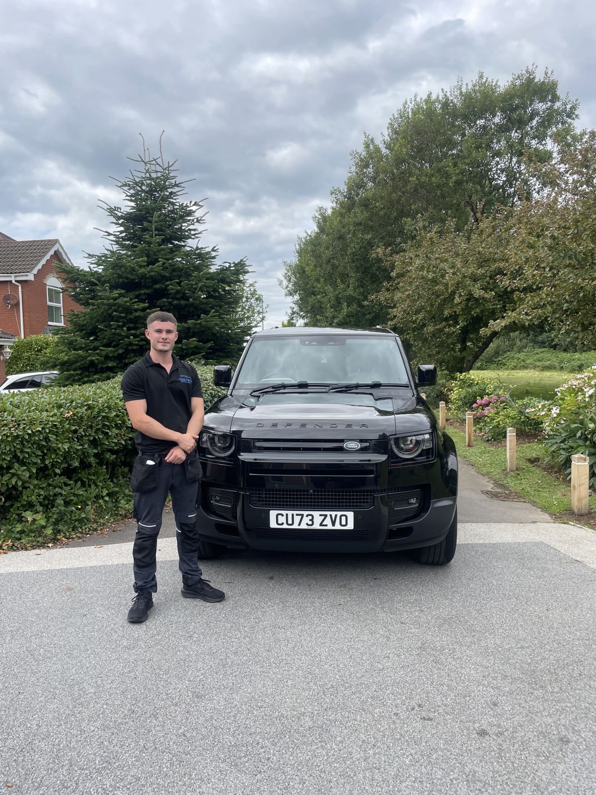 Chauvel's Detailing owner in uniform with a black Land Rover Defender after detailing in Bridgend